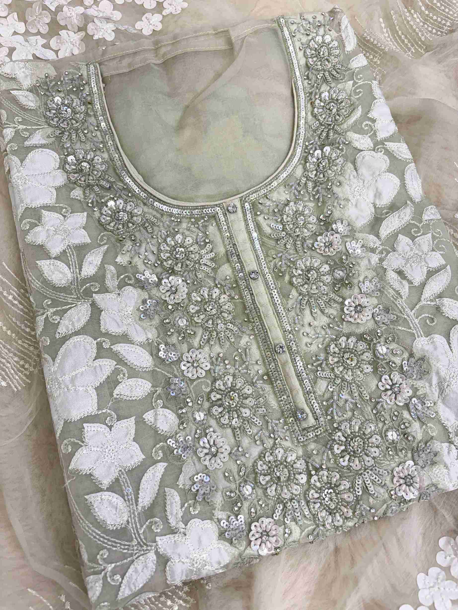 Close-up of all-over white floral applique work across the full body of mint green organza shirt