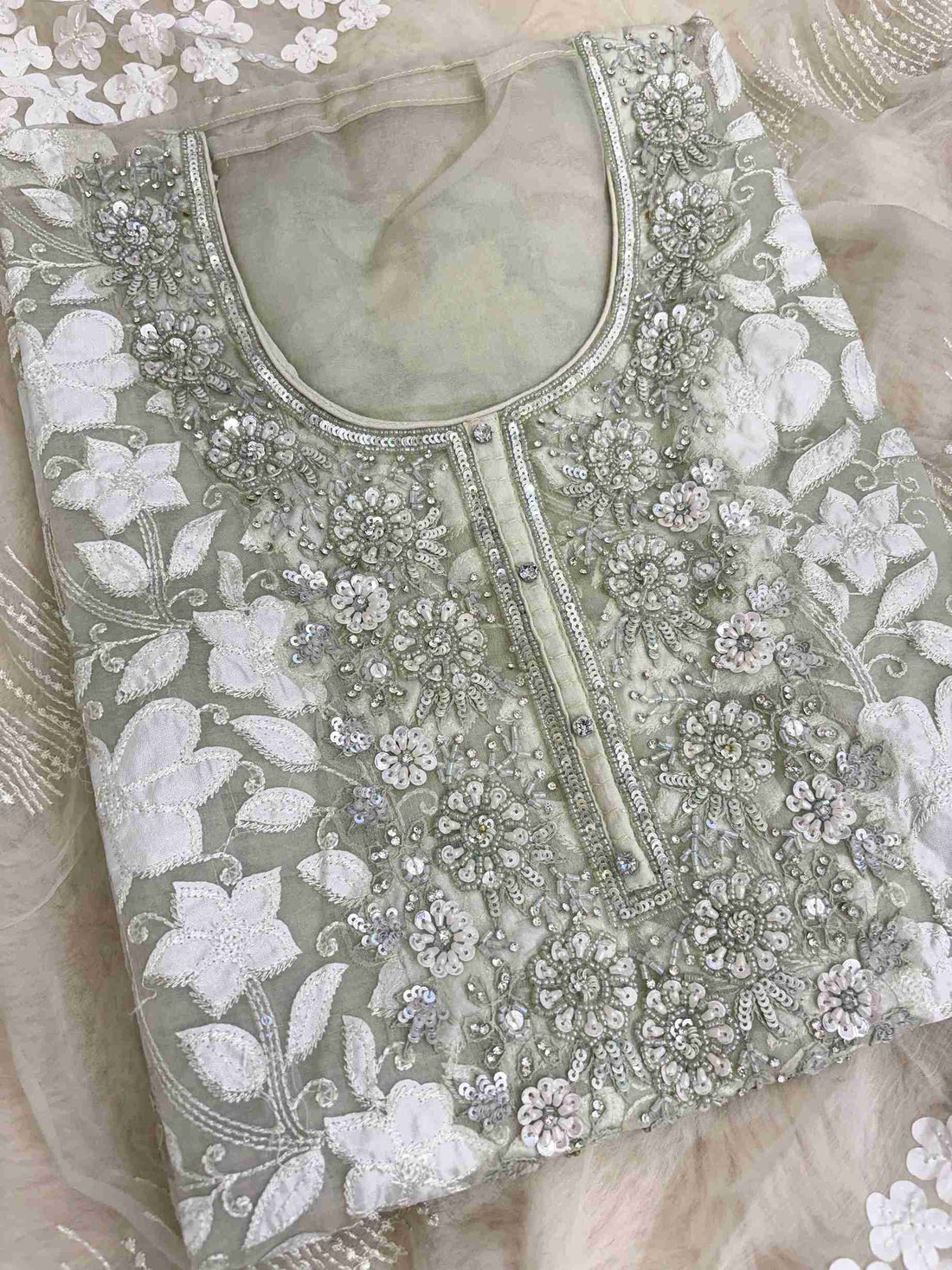 Close-up of all-over white floral applique work across the full body of mint green organza shirt