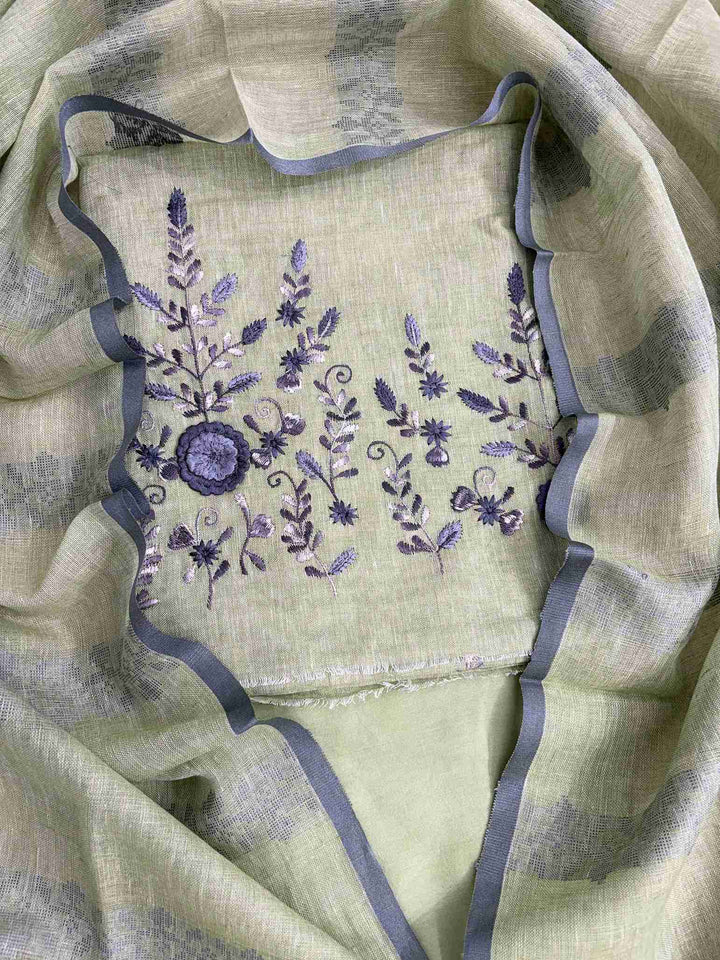 Close-up of contrasting thread embroidery with floral and botanical motifs on mint green linen shirt hemline