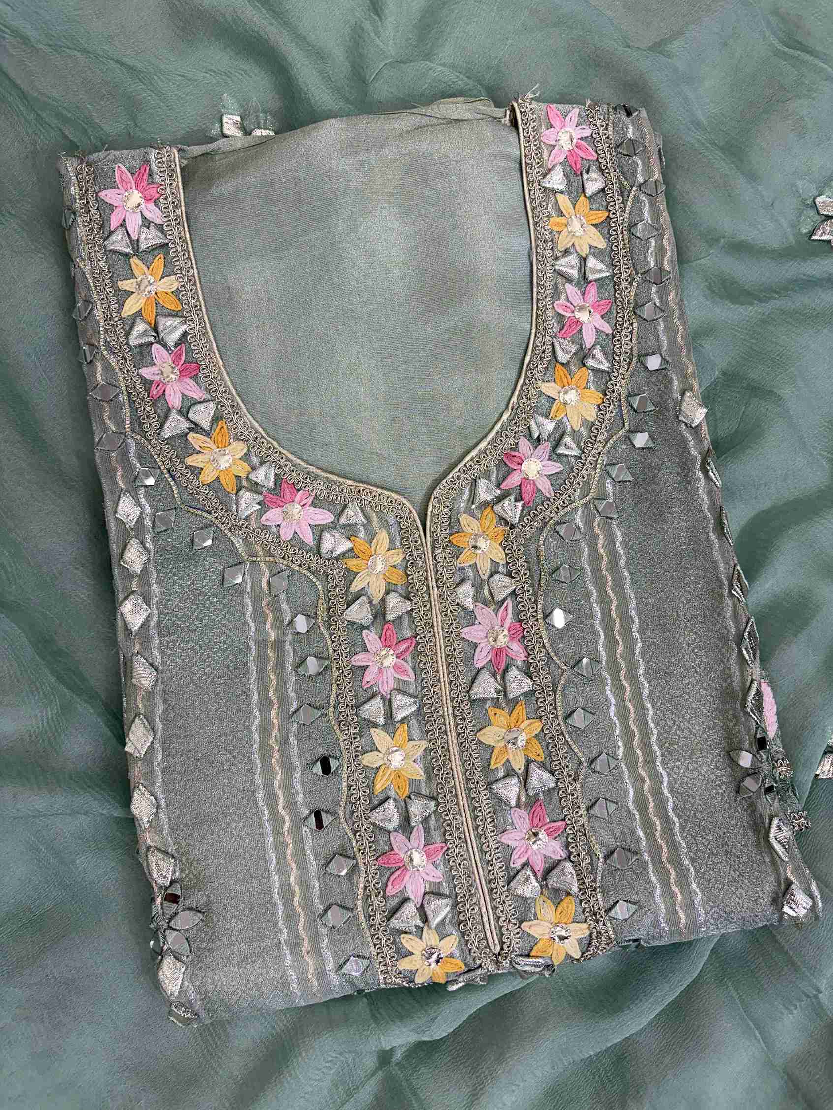 Multicolor thread floral motifs with mirror work and gota highlighting at neckline of mint green shimmer tissue shirt