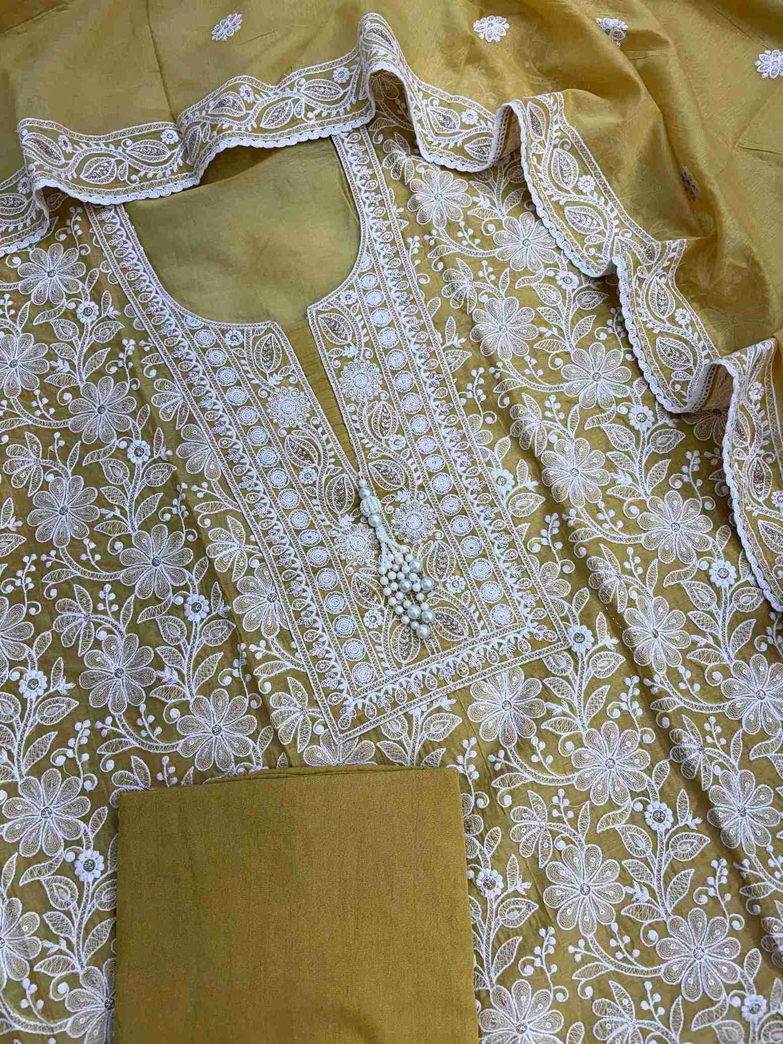 Detailed white resham thread embroidery with zari highlights on mustard fabric
