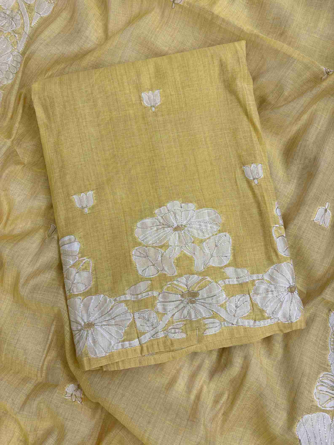 Close-up of woven floral vine hemline with golden thread highlights on mustard suit
