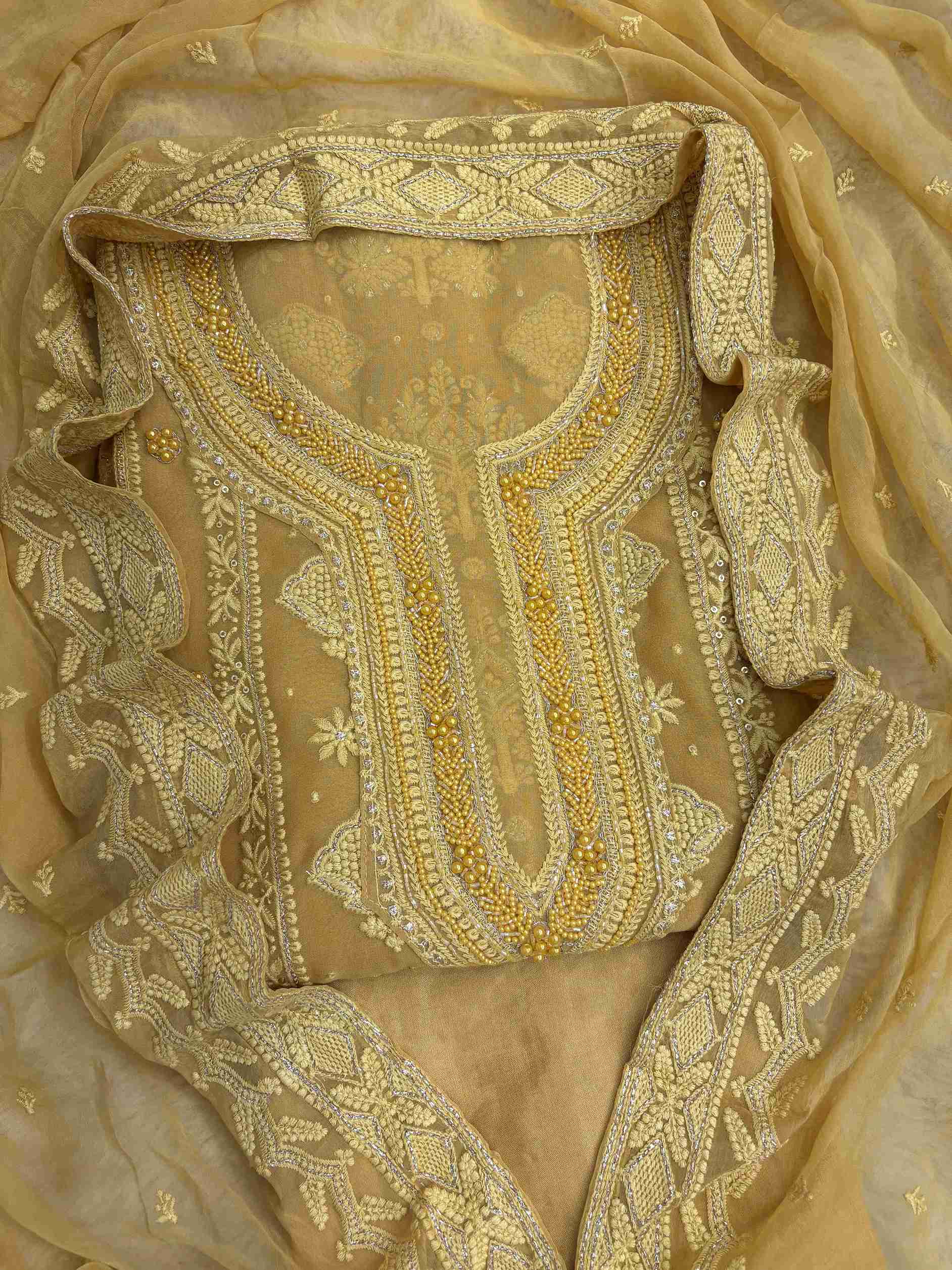 Mustard yellow georgette unstitched suit front view with heavy neckline embroidery and chiffon dupatta