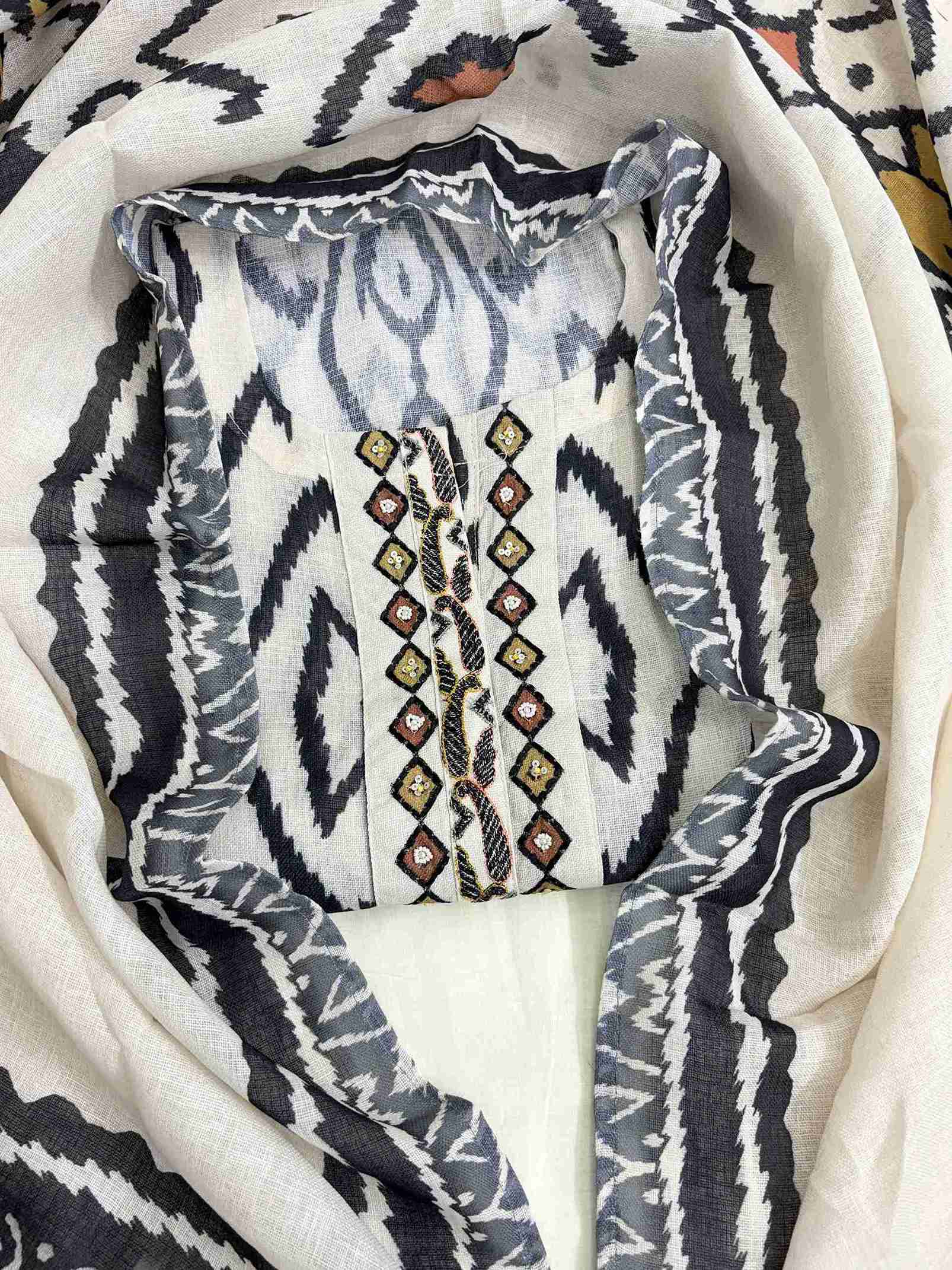 Embroidered neckline panel with multicolor thread and bead detailing on off-white black ikat linen shirt