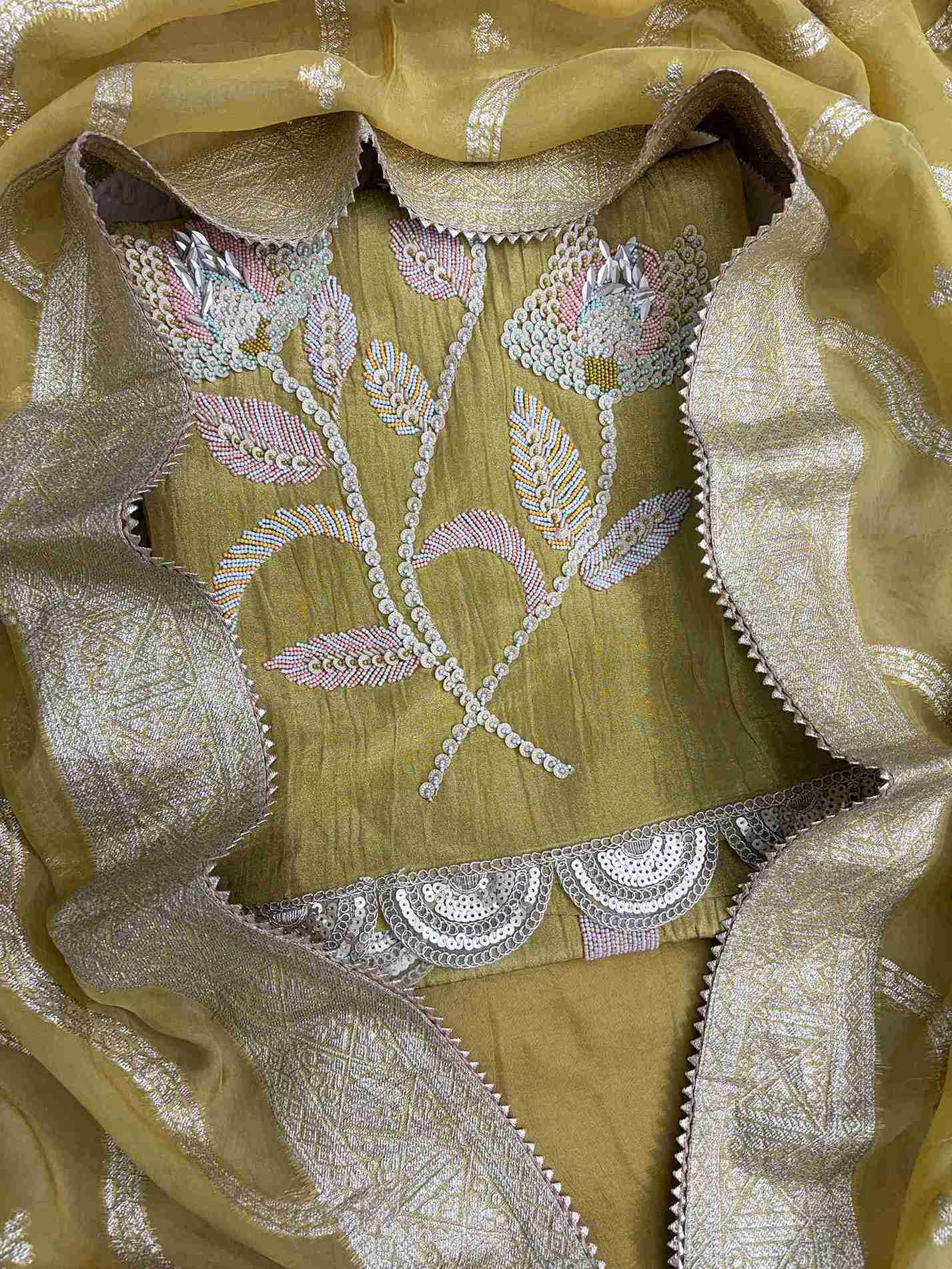 Close-up of heavy sequin, nalki, and cutdana embellishment at hemline of olive gold crushed tissue shirt