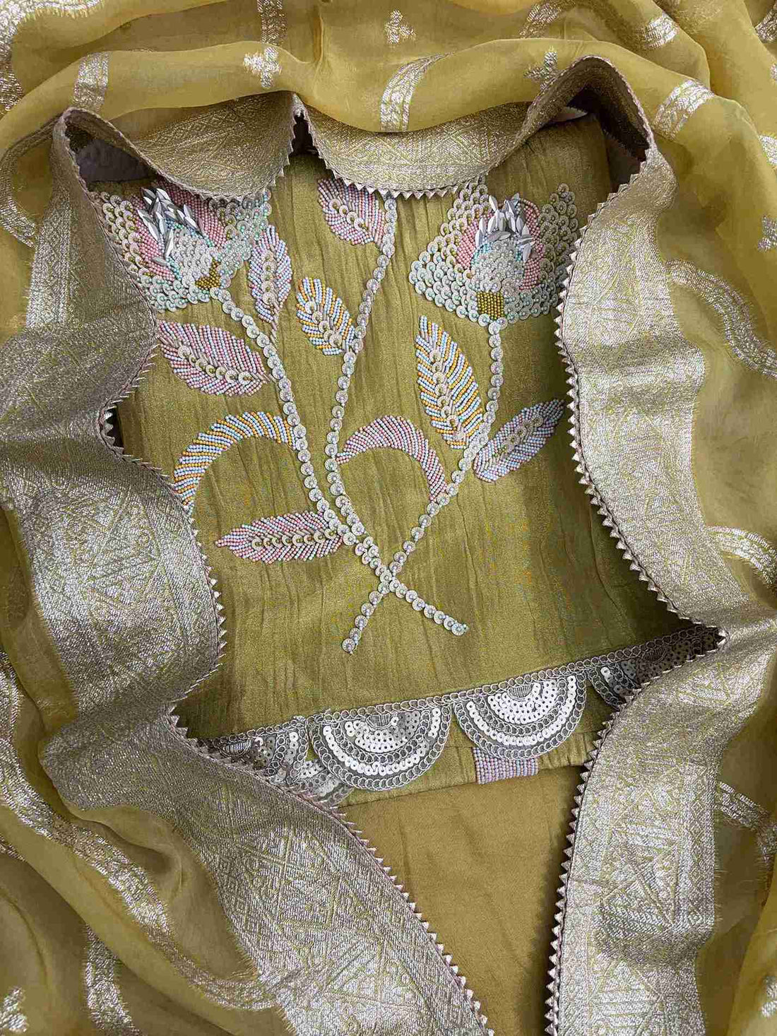 Close-up of heavy sequin, nalki, and cutdana embellishment at hemline of olive gold crushed tissue shirt