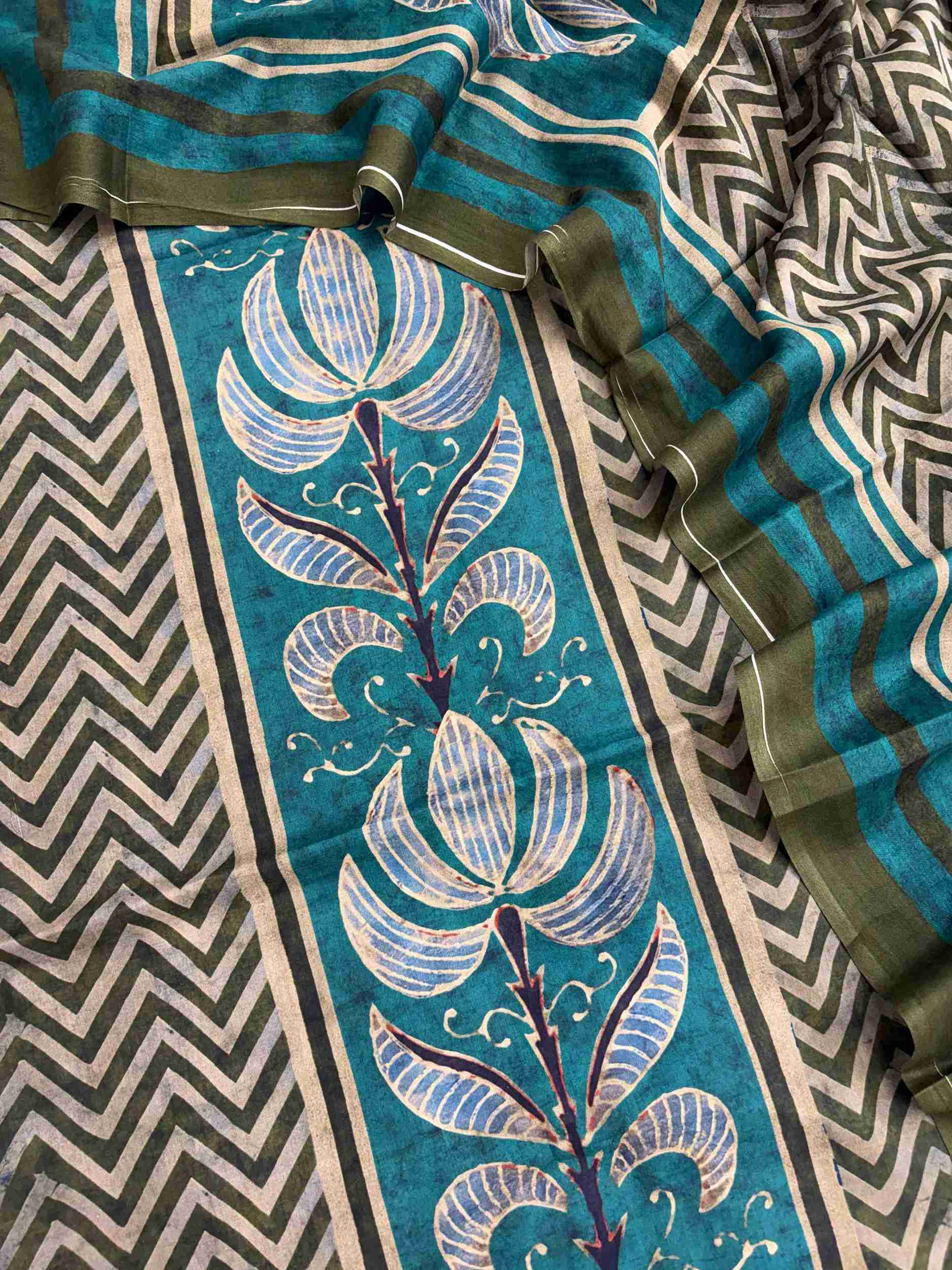 Large teal floral motifs at end panel of olive green mul cotton dupatta with dark olive stripe border