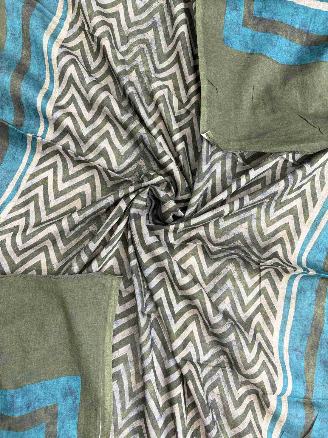 Large teal and cream floral inspired motifs on central front panel of olive green mul cotton shirt