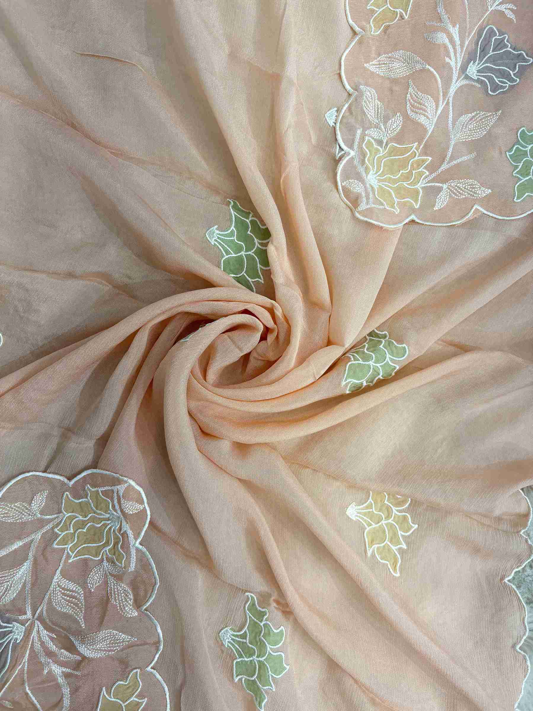 Applique floral motif highlighted with thread embroidery at center of peach chinnon dupatta