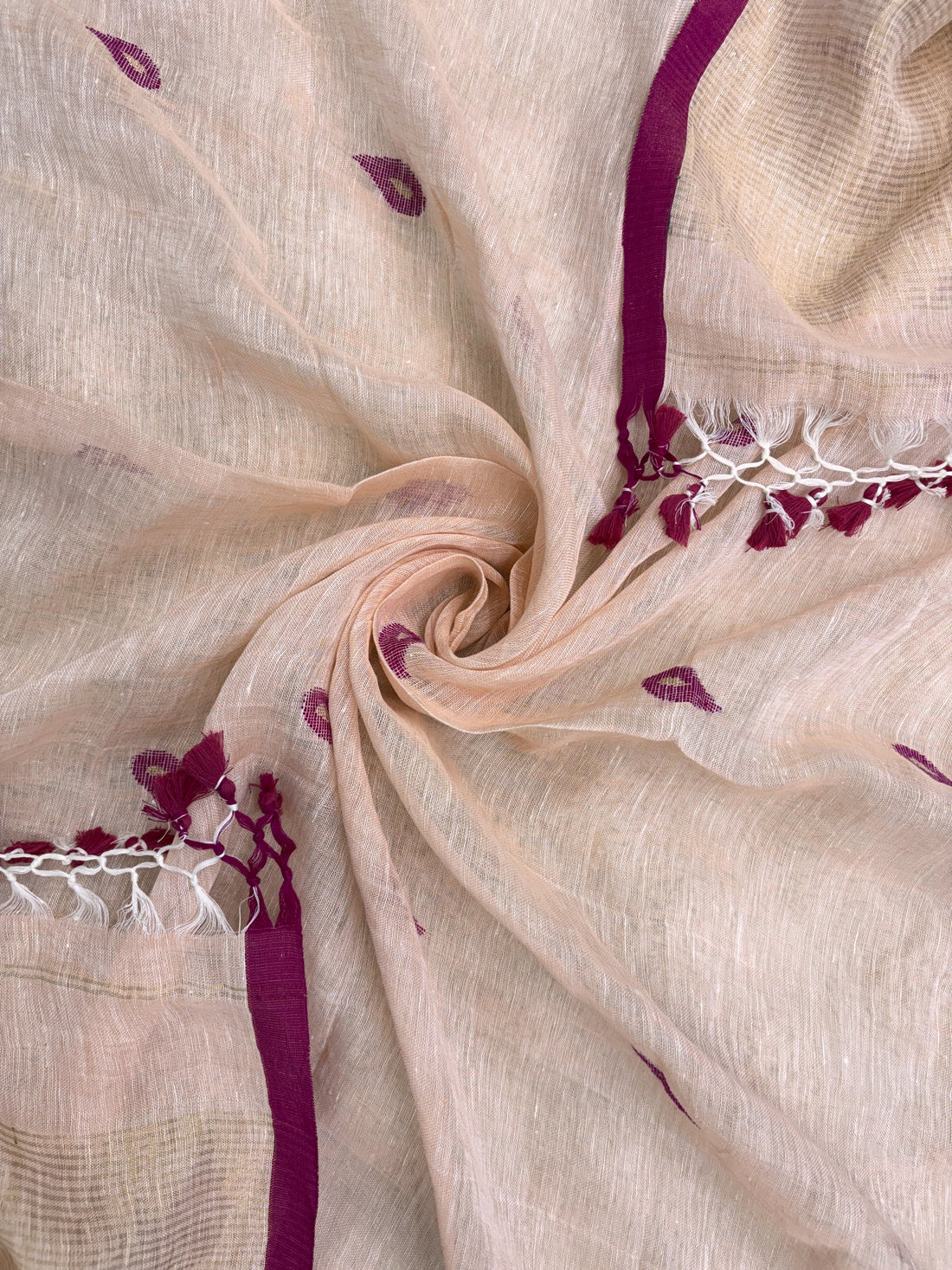 Scattered small pink paisley woven motifs across peach linen dupatta surface
