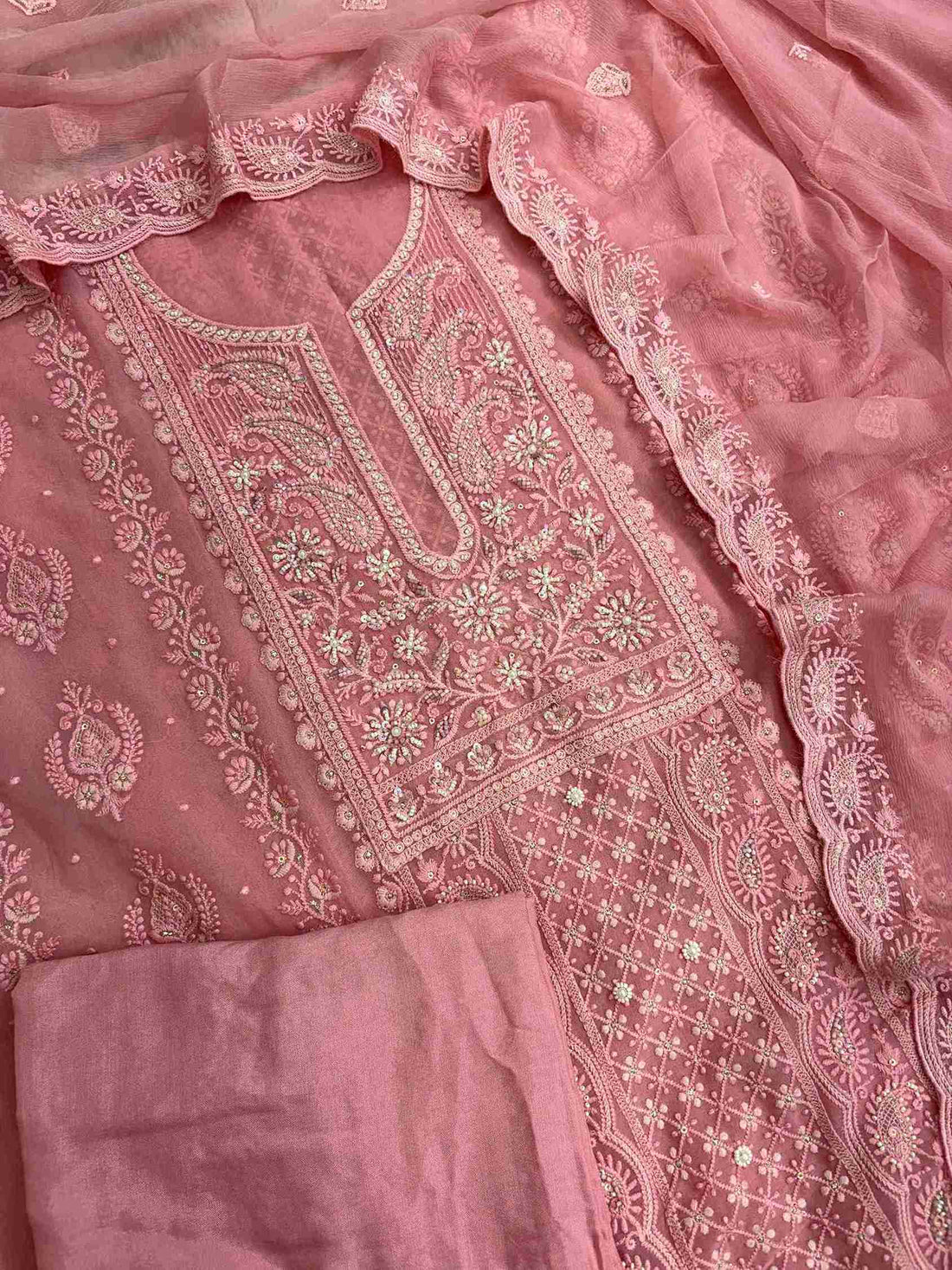 Complete peach pink georgette unstitched suit flat lay set with chikankari shirt, chiffon dupatta, and cotton silk bottom