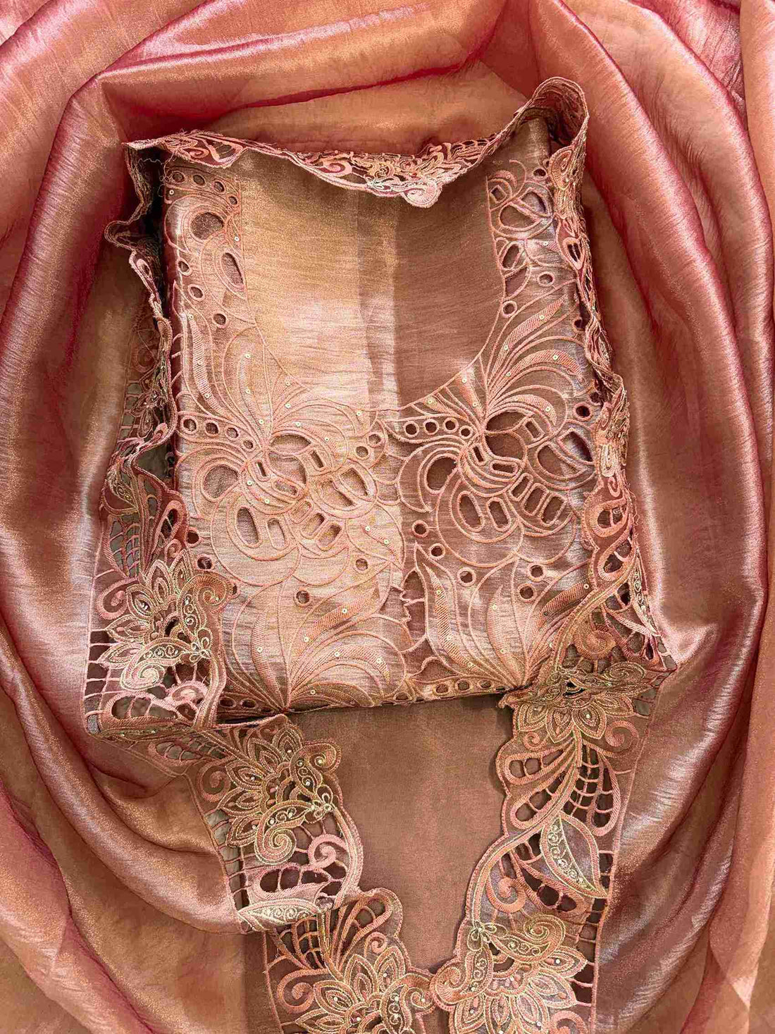 Cutwork detailing along the hemline of peach shimmer tissue suit