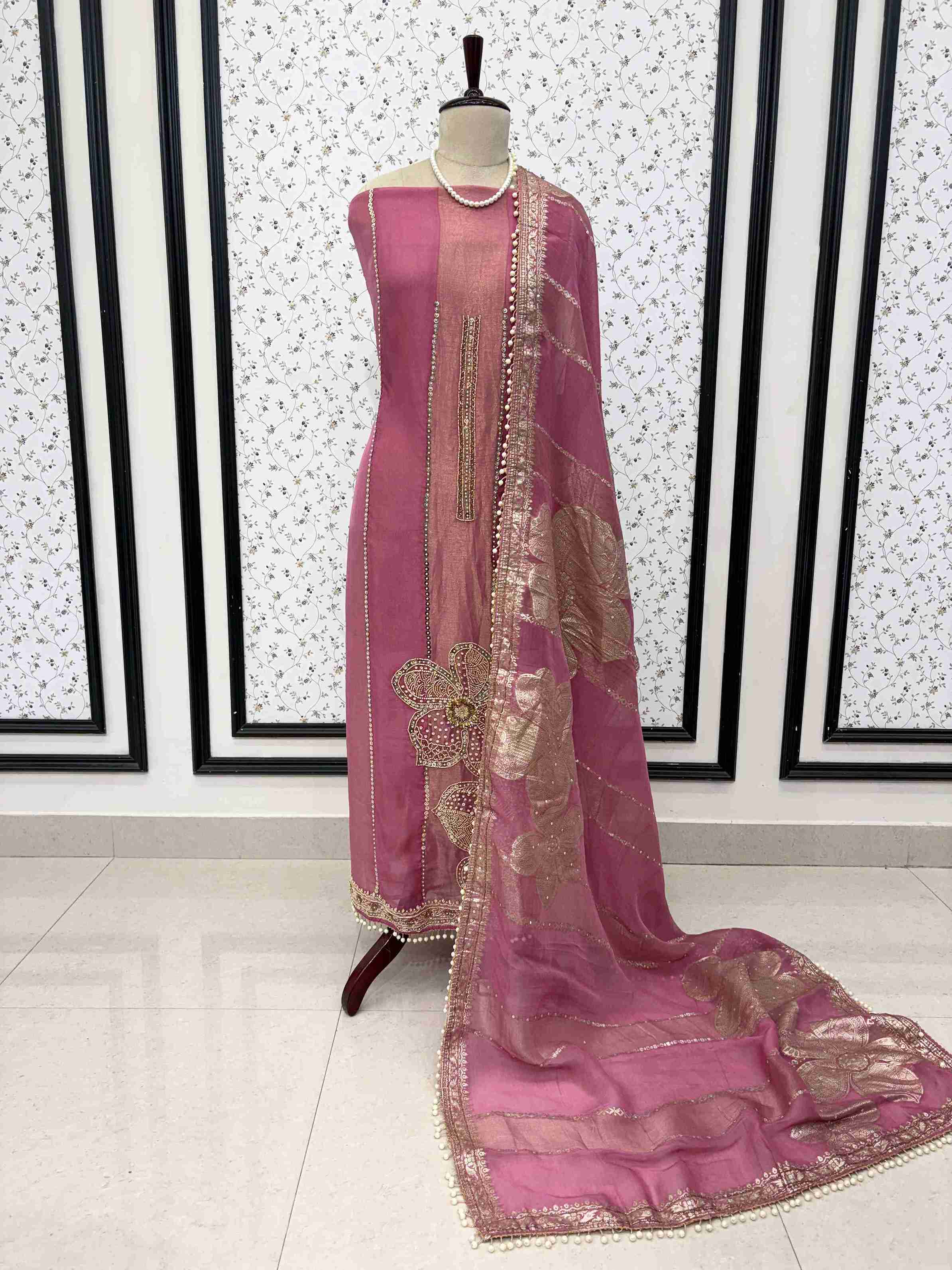 Pink shimmer organza unstitched suit set displayed on mannequin with cutdana hemline and Banarasi dupatta
