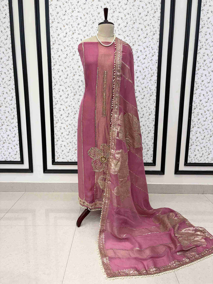 Pink shimmer organza unstitched suit set displayed on mannequin with cutdana hemline and Banarasi dupatta