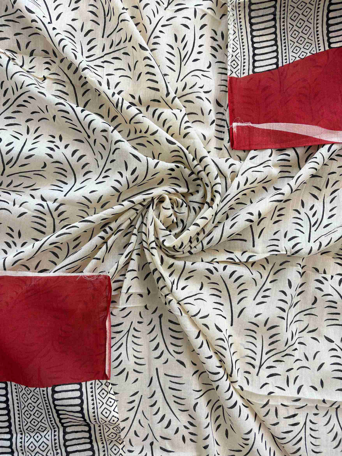 Detailed view of red and off white printed cotton suit fabric combination