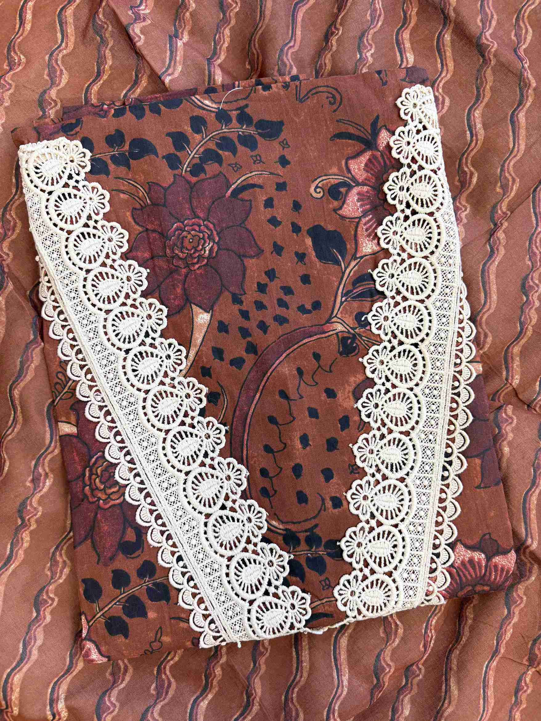 V-shaped neckline with broad crotia lace highlighting and decorative shell and coin tassels on rust brown cotton shirt