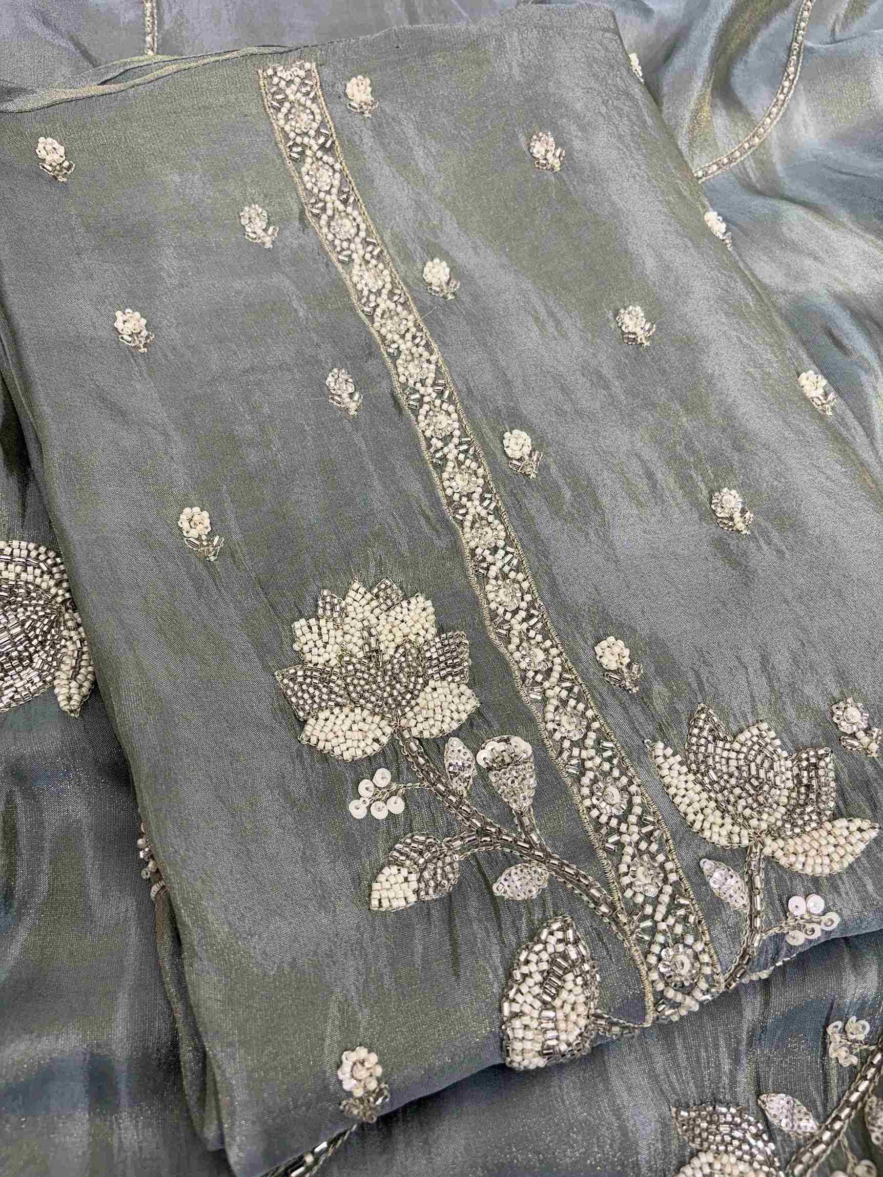 Close-up of richly embellished neckline with thread embroidery, pearls, nalki, beads, and sequins on sage grey-green soft tissue shirt