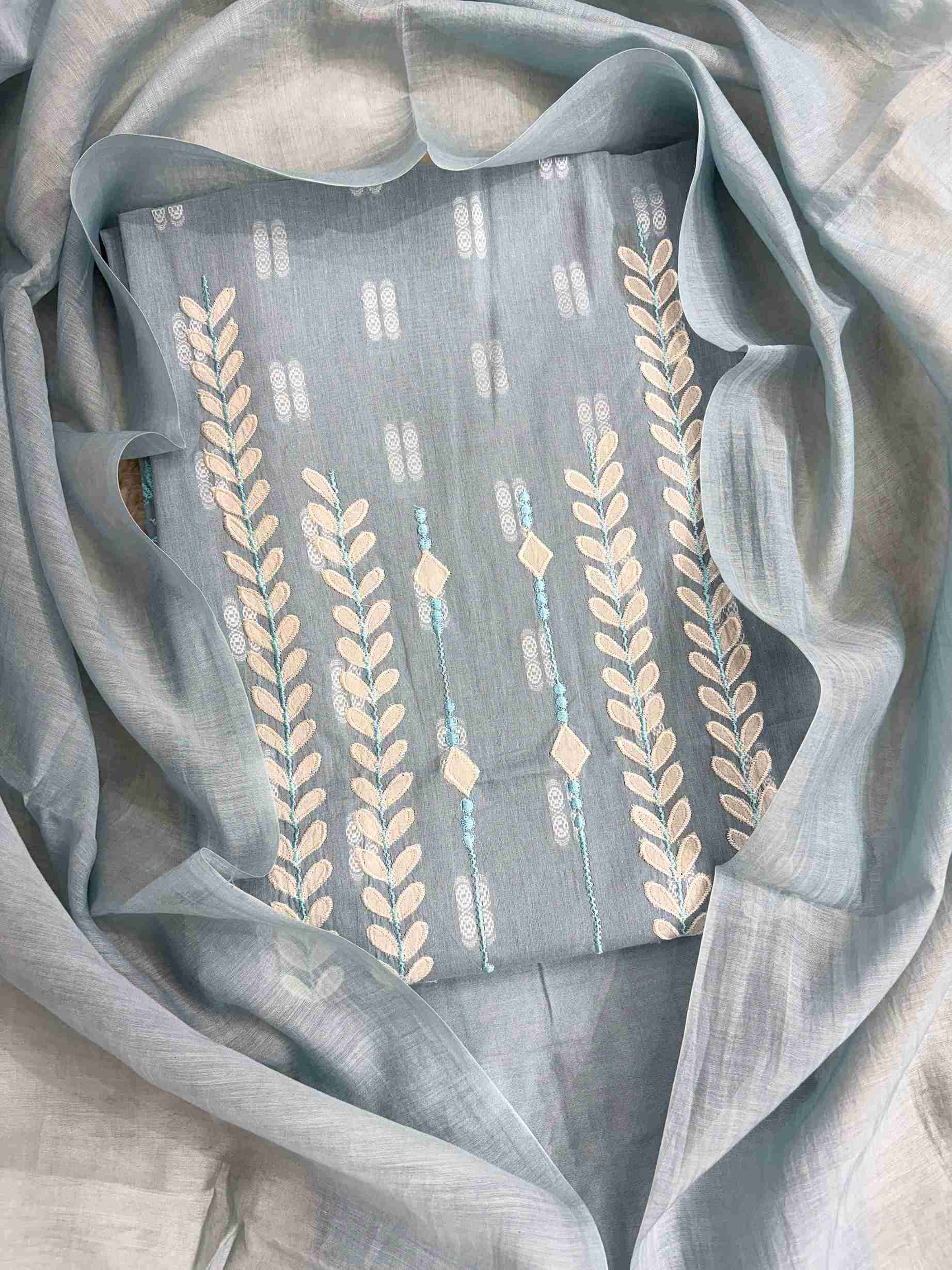Close-up of white applique leaf and vine motif columns at neckline of steel blue cotton shirt