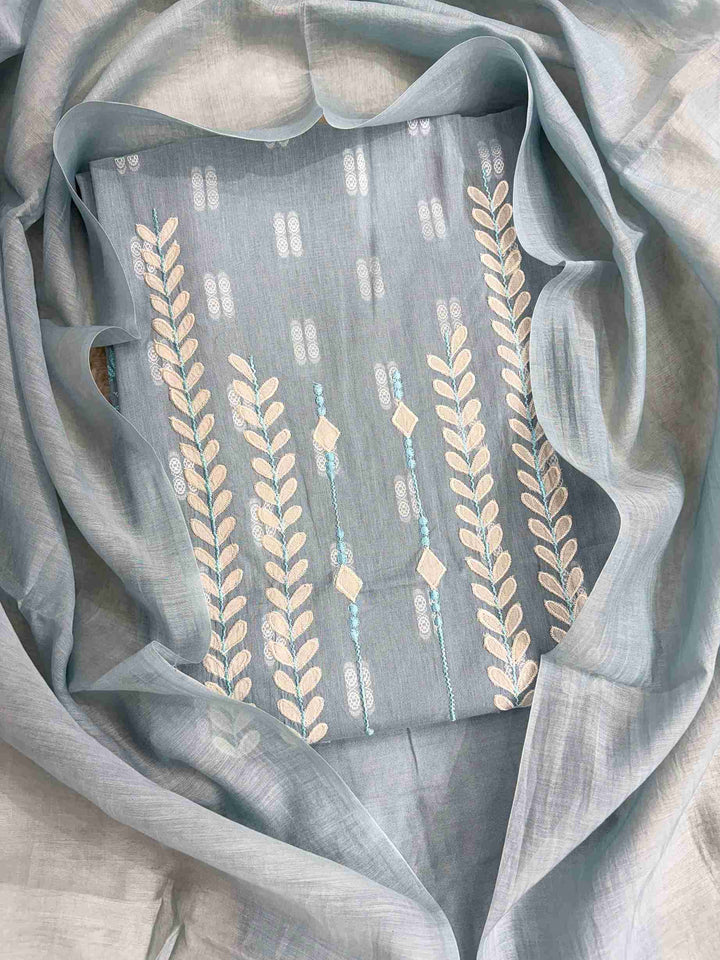 Close-up of white applique leaf and vine motif columns at neckline of steel blue cotton shirt