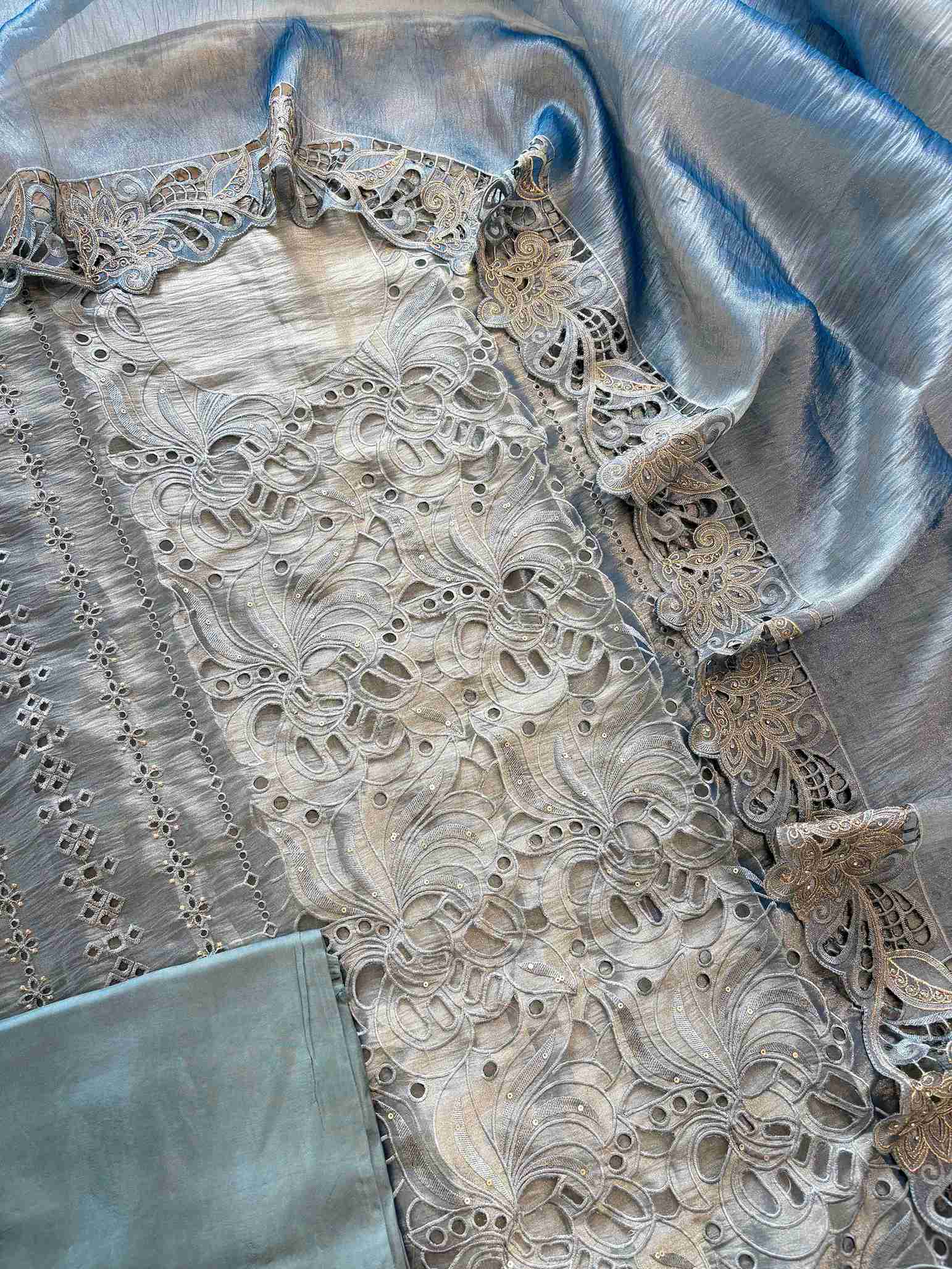 Cutwork detailing along the hemline of steel blue shimmer tissue suit