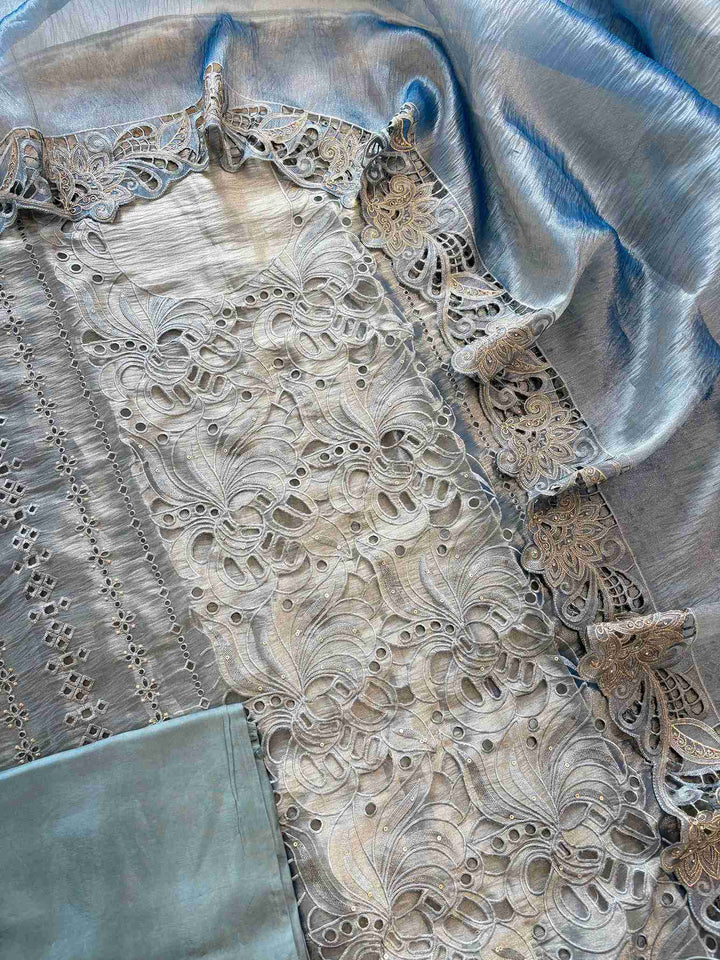 Cutwork detailing along the hemline of steel blue shimmer tissue suit