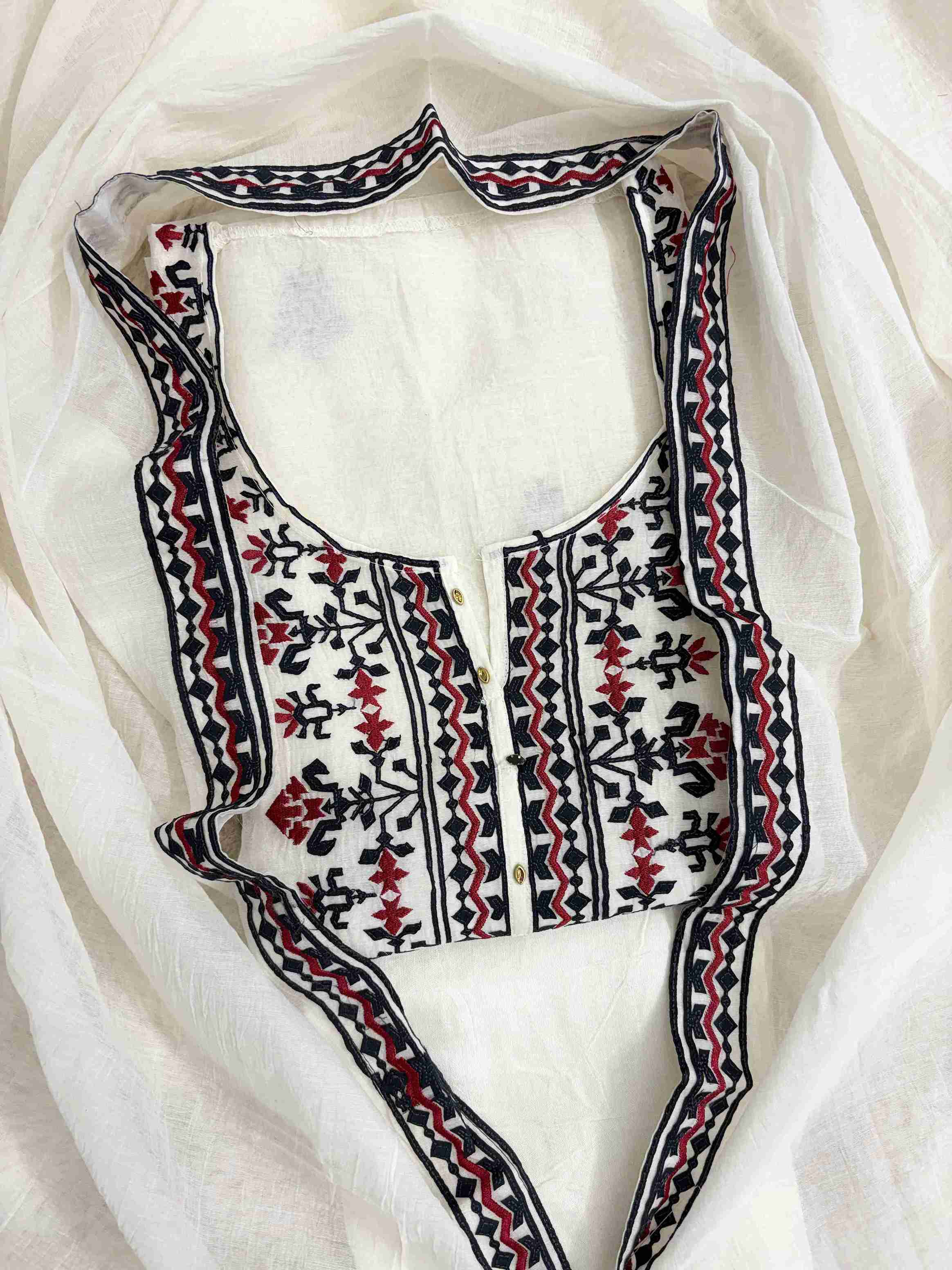 Dense black applique and red thread embroidered geometric neckline panel on white mul chanderi shirt