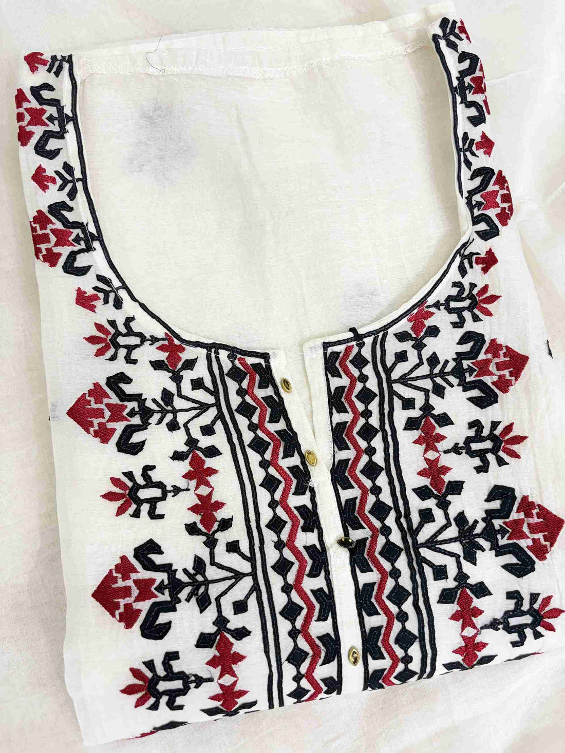 Scattered black applique and red thread geometric motifs across white mul chanderi shirt body