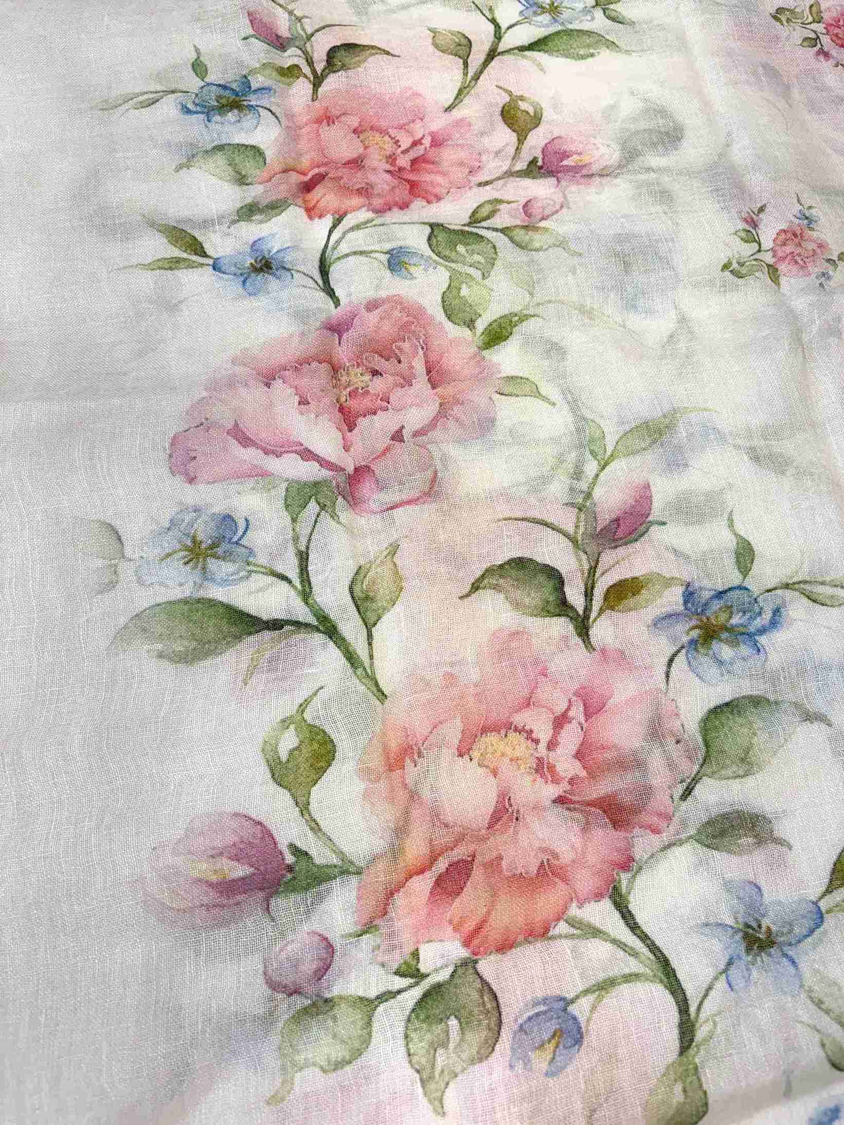 Close-up of digital multicolor floral print with roses and green leaves on white pure linen shirt hemline