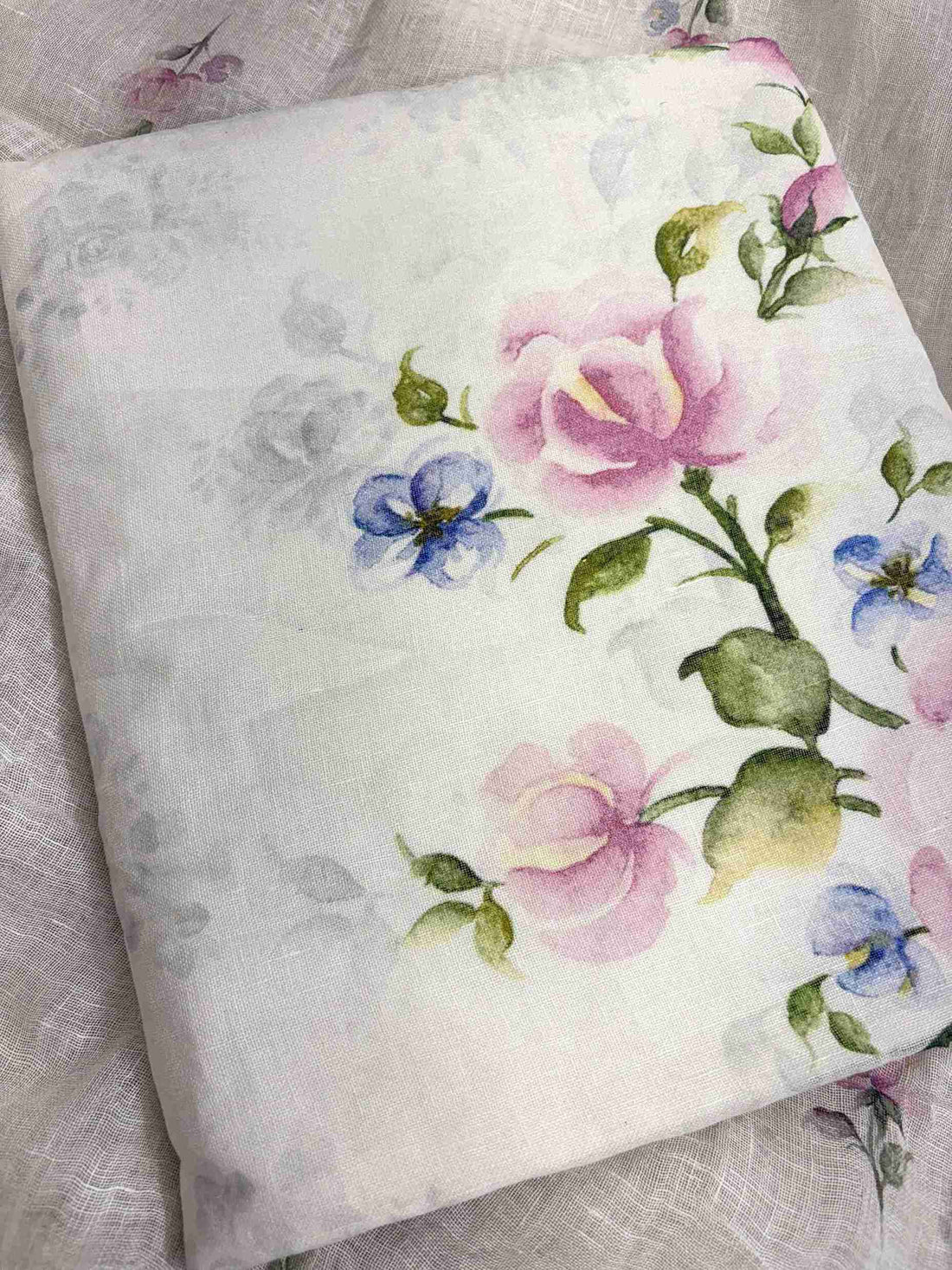 Close-up of digital mauve-pink roses and blue accent flowers on white pure linen shirt hemline