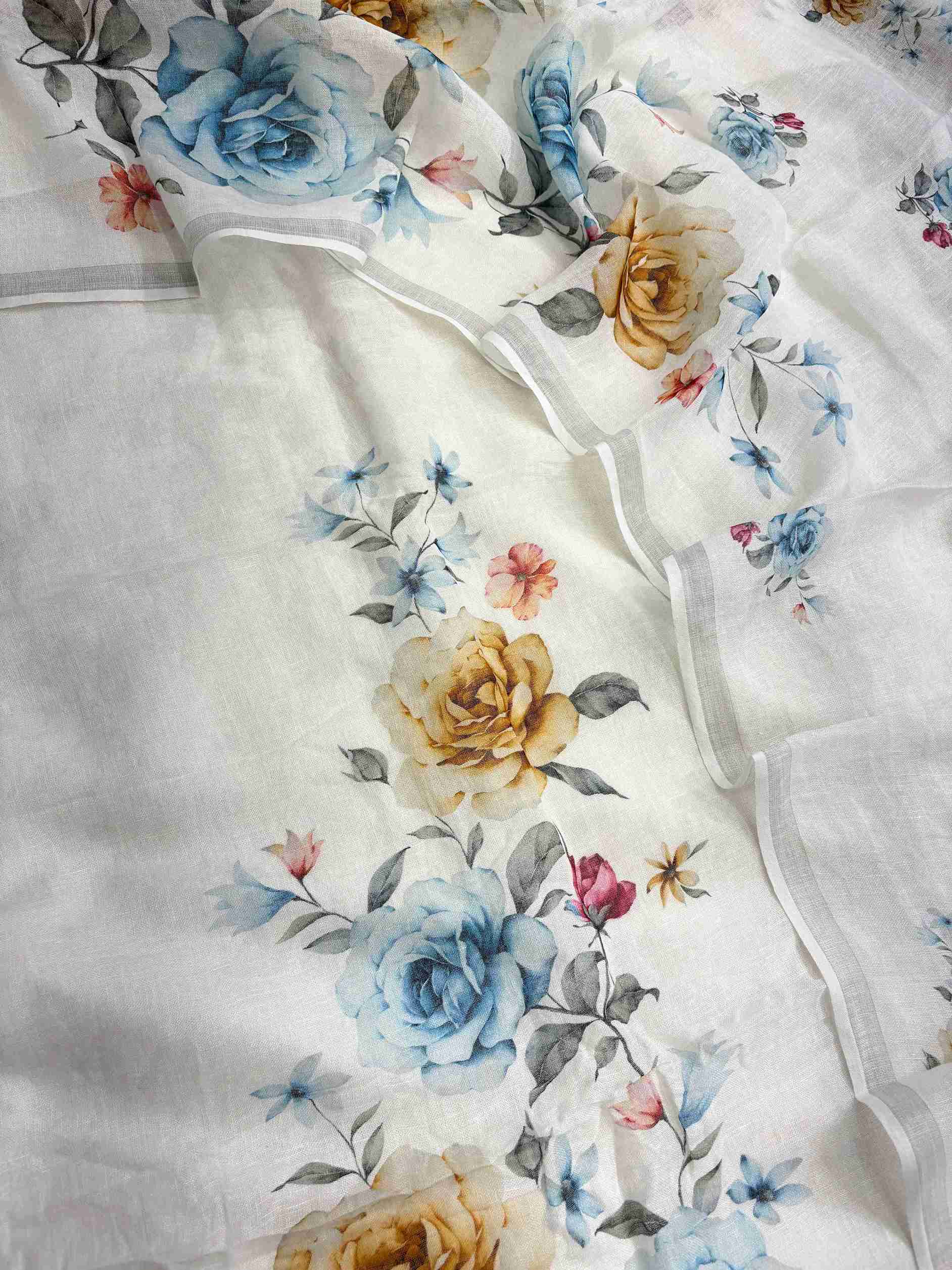 Complete white pure linen unstitched suit flat lay set with shirt, dupatta, and linen bottom showing blue and golden floral print