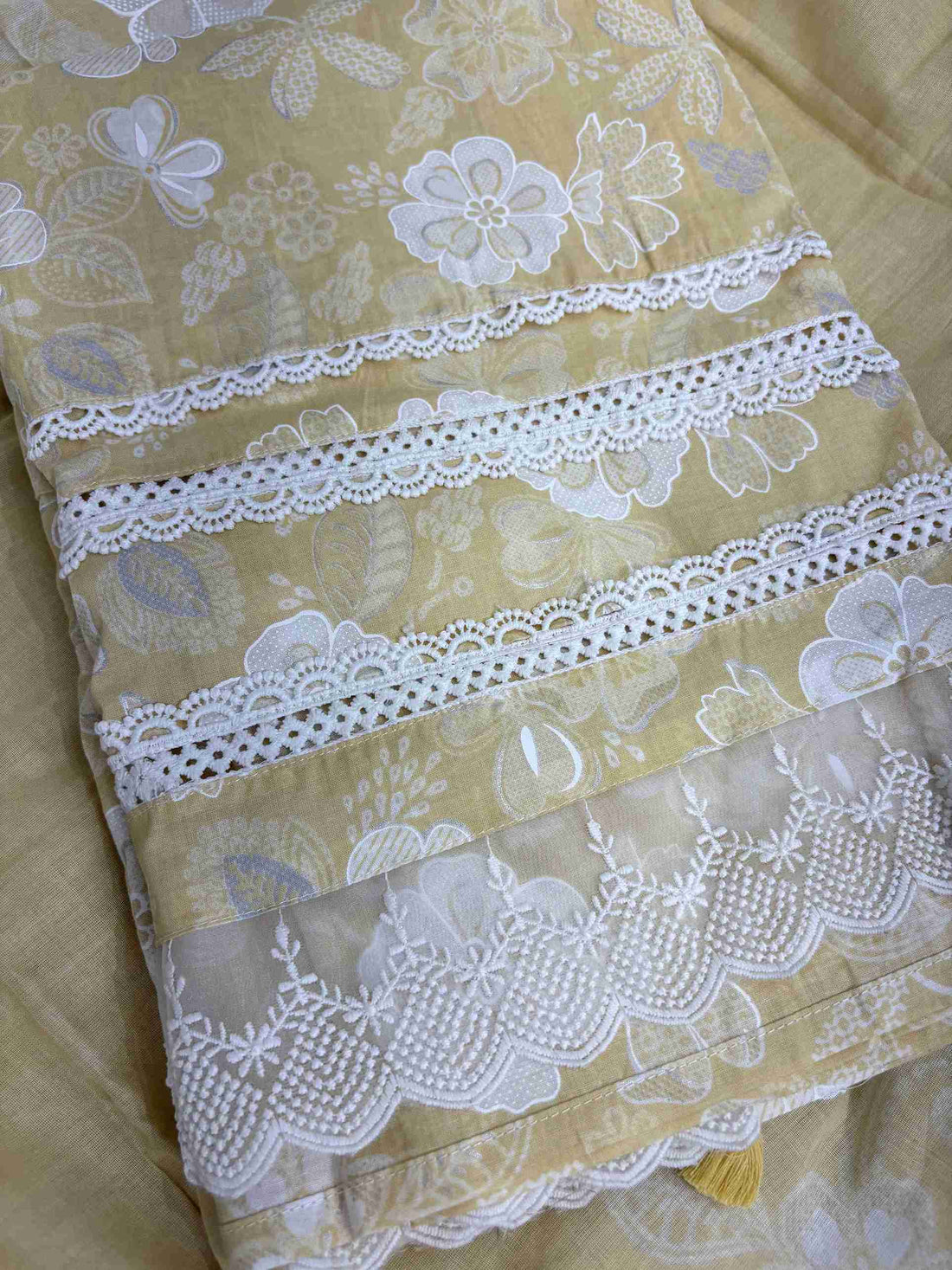Multiple row crotia lace hemline finishing detail at the bottom of yellow cotton shirt