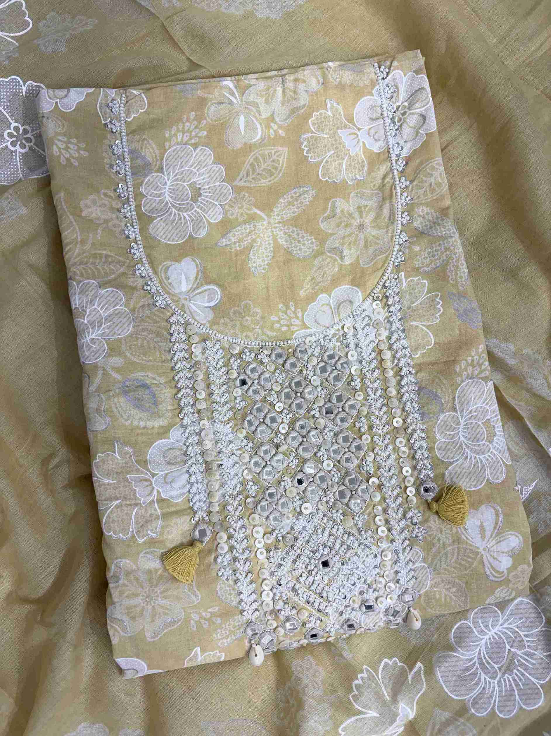 Close-up of mirror work, sequin and moti embellished neckline panel with tassels on yellow cotton shirt