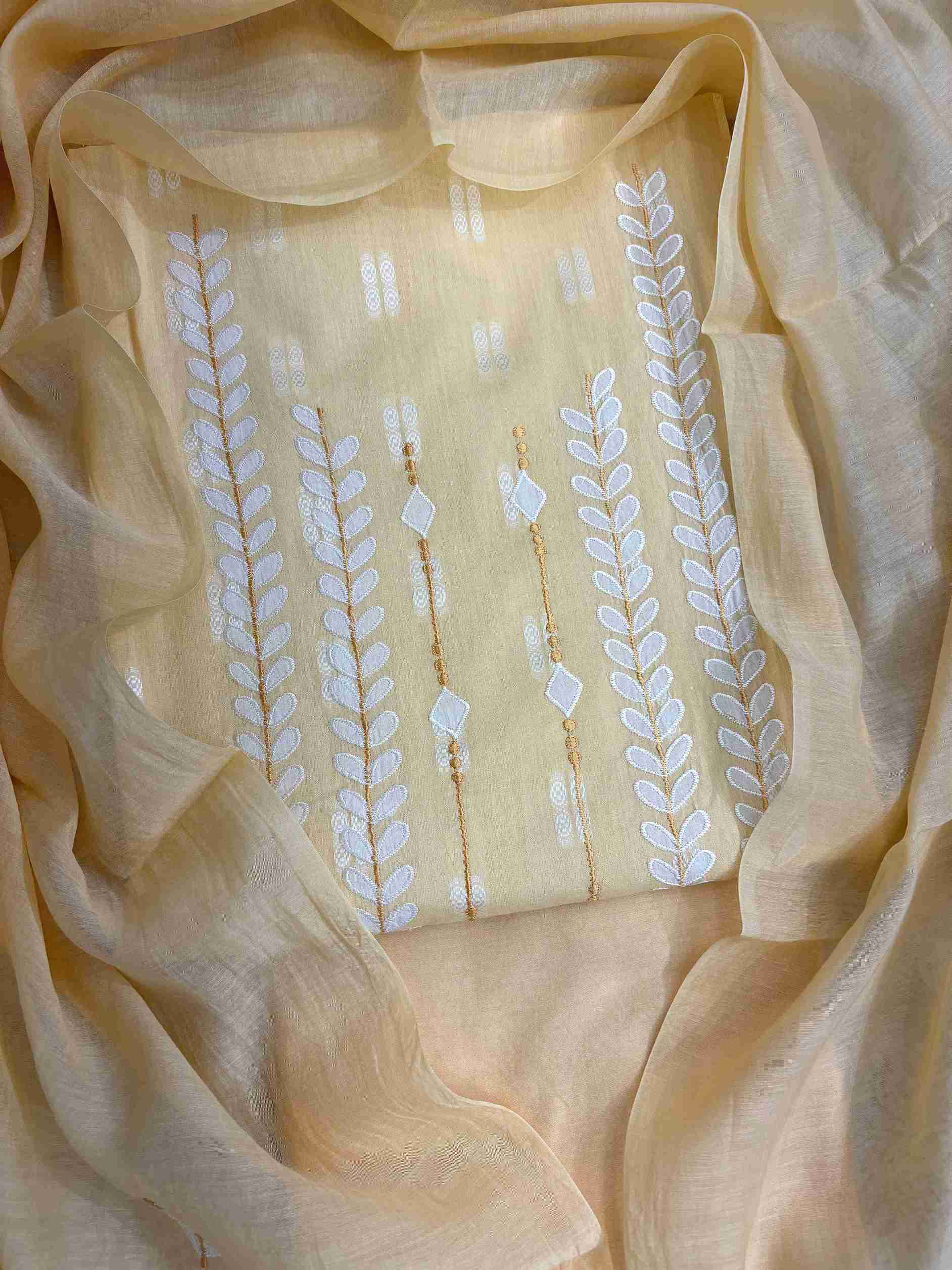 Close-up of white applique leaf and vine motif columns at neckline of yellow cotton shirt