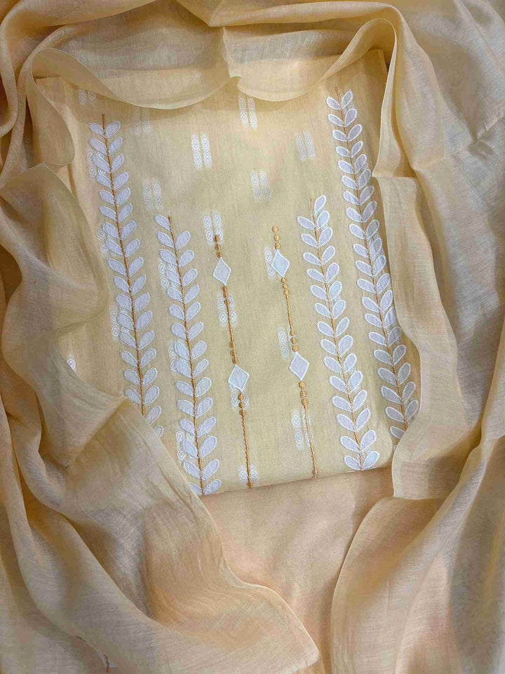 Close-up of white applique leaf and vine motif columns at neckline of yellow cotton shirt