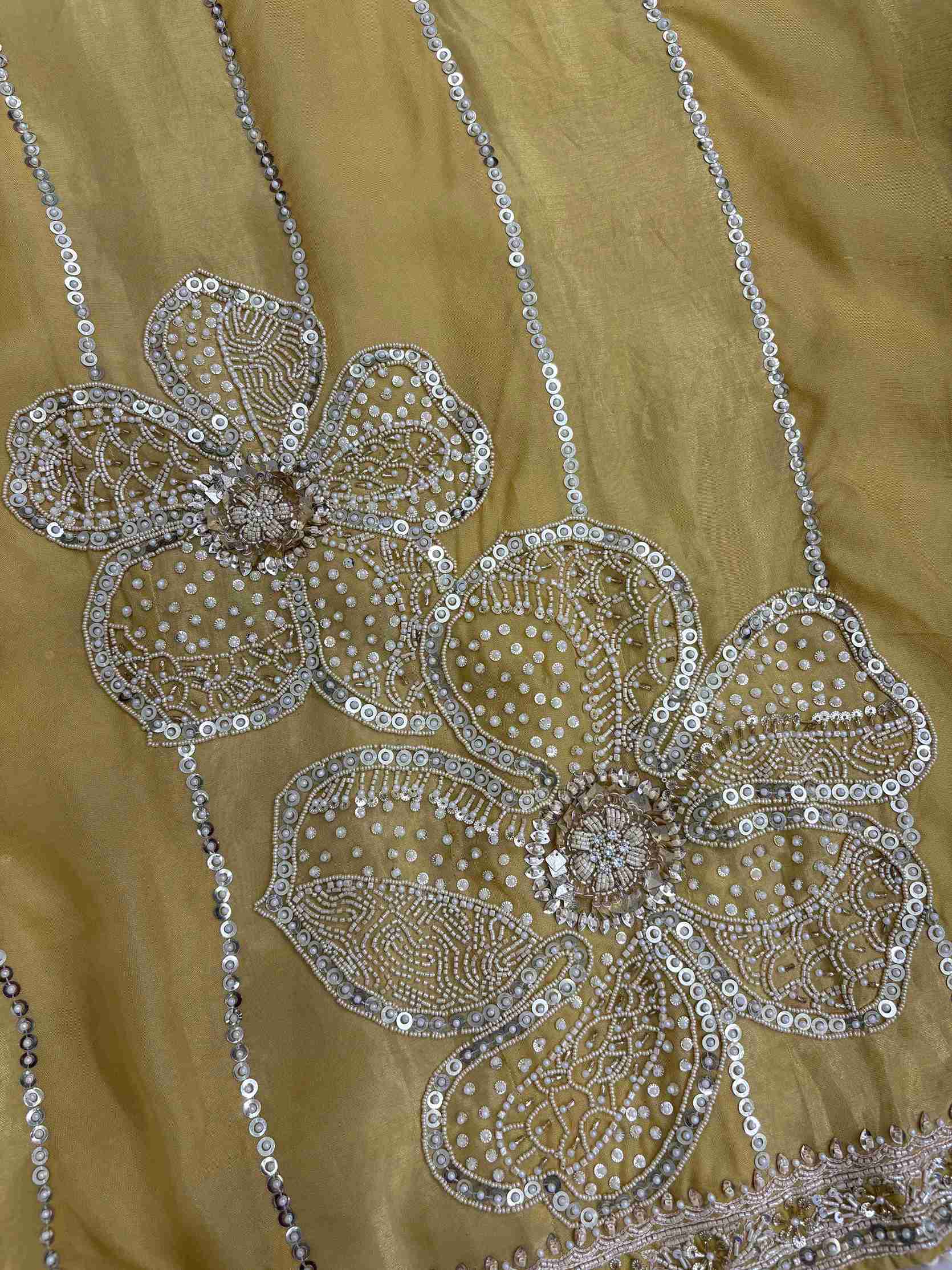 Close-up of yellow organza shirt hemline featuring intricate cutdana handwork