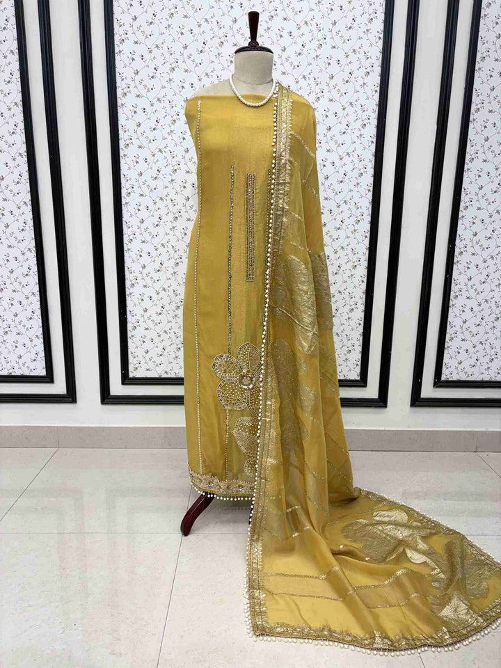 yellow shimmer organza unstitched suit set displayed on mannequin with cutdana hemline and Banarasi dupatta